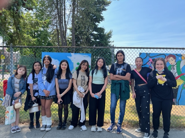 Mural Club participants from John Oliver High School stand by their art hung along Fraser Street school fence and are joined by artist and instructor Mara Cortez